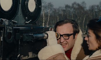 Movie still from “A Man and a Woman” (1966), directed by Claude Lelouch – A man looking through the lens of an old fashioned movie camera; Close Up shot, Low angle