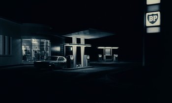 Movie still from “A Man and a Woman” (1966), directed by Claude Lelouch – A gas station at night with a car parked in front of it; Extreme Wide shot, Low angle