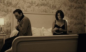 Movie still from “A Man and a Woman” (1966), directed by Claude Lelouch – A man and a woman sitting on a bed; Medium shot, High angle