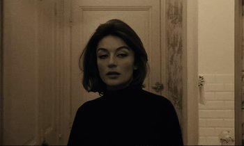 Movie still from “A Man and a Woman” (1966), directed by Claude Lelouch – A woman in a black shirt standing in front of a door; Close Up shot, Low angle
