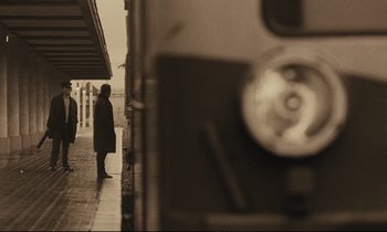 Movie still from “A Man and a Woman” (1966), directed by Claude Lelouch – A man standing on the side of a train platform next to a train; Wide shot, Low angle