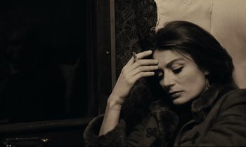 Movie still from “A Man and a Woman” (1966), directed by Claude Lelouch – A woman sitting on a train with her hand on her head; Close Up shot, High angle