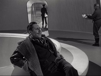 Movie still from “A Matter of Life and Death” (1946), directed by Emeric Pressburger – A black and white photo of a man sitting on a chair; Wide shot, Low angle