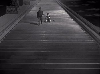 Movie still from “A Matter of Life and Death” (1946), directed by Emeric Pressburger – A man walking up a flight of stairs with a child sitting on the ground; Wide shot, High angle