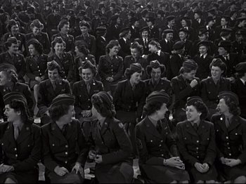 Movie still from “A Matter of Life and Death” (1946), directed by Emeric Pressburger – A large group of women in uniform sitting in a field; Wide shot, High angle