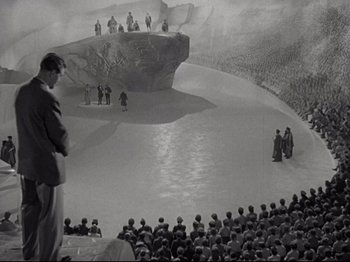 Movie still from “A Matter of Life and Death” (1946), directed by Emeric Pressburger – A crowd of people are gathered around a stage; Extreme Wide shot, High angle