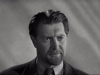 Movie still from “A Matter of Life and Death” (1946), directed by Emeric Pressburger – An old photo of a man in a suit and tie; Close Up shot, Over the shoulder angle
