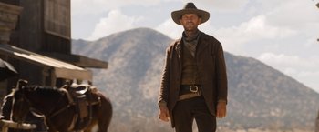 Movie still from “A Million Ways to Die in the West” (2014), directed by Seth MacFarlane – A man wearing a cowboy hat standing next to a horse; Medium shot, Low angle