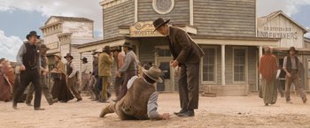 Movie still from “A Million Ways to Die in the West” (2014), directed by Seth MacFarlane – Two men in hats and vests are on the ground; Wide shot, Over the shoulder angle