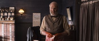 Movie still from “A Million Ways to Die in the West” (2014), directed by Seth MacFarlane – An older man holding a piece of meat in his hands; Medium shot, Low angle