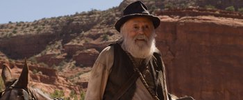 Movie still from “A Million Ways to Die in the West” (2014), directed by Seth MacFarlane – An old man with a beard wearing a black hat; Medium shot, Over the shoulder angle