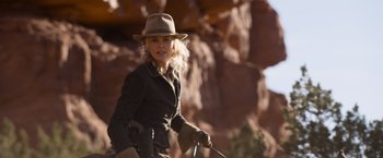 Movie still from “A Million Ways to Die in the West” (2014), directed by Seth MacFarlane – A woman in a hat and riding gear on a horse; Medium shot, Over the shoulder angle