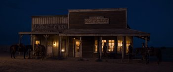 Movie still from “A Million Ways to Die in the West” (2014), directed by Seth MacFarlane – A man walking in front of a restaurant at night; Extreme Wide shot, Low angle