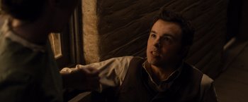 A man in a vest is pointing to the side