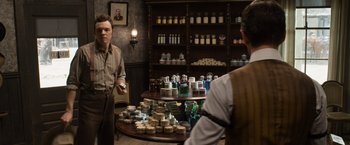 Movie still from “A Million Ways to Die in the West” (2014), directed by Seth MacFarlane – Two men are standing in front of a table full of jars; Medium shot, Over the shoulder angle
