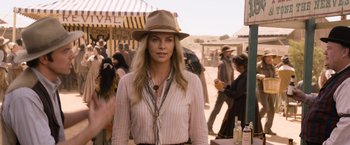 Movie still from “A Million Ways to Die in the West” (2014), directed by Seth MacFarlane – A woman wearing a hat standing next to a crowd of onlookers; Medium shot, Over the shoulder angle