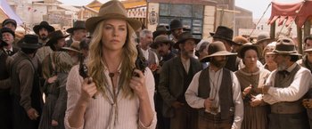 Movie still from “A Million Ways to Die in the West” (2014), directed by Seth MacFarlane – A group of people standing in a crowd holding guns; Medium shot, Over the shoulder angle