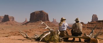 Movie still from “A Million Ways to Die in the West” (2014), directed by Seth MacFarlane – A woman sitting on the ground in front of a rock formation; Wide shot, Over the shoulder angle