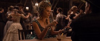 Movie still from “A Million Ways to Die in the West” (2014), directed by Seth MacFarlane – A woman sitting at a table with a glass of wine; Medium shot, Over the shoulder angle