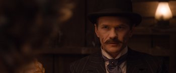 Movie still from “A Million Ways to Die in the West” (2014), directed by Seth MacFarlane – A man with a mustache wearing a suit and a hat; Close Up shot, Low angle