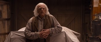 Movie still from “A Million Ways to Die in the West” (2014), directed by Seth MacFarlane – An old man with long white hair is standing in front of a bed; Medium shot, Over the shoulder angle