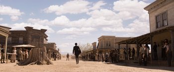 Movie still from “A Million Ways to Die in the West” (2014), directed by Seth MacFarlane – A group of people standing in front of a building; Extreme Wide shot, Low angle