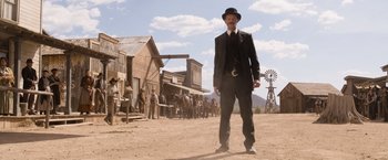 Movie still from “A Million Ways to Die in the West” (2014), directed by Seth MacFarlane – A man in a suit and hat standing in front of a group of people; Wide shot, Low angle