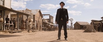 Movie still from “A Million Ways to Die in the West” (2014), directed by Seth MacFarlane – A man in a suit and hat walking in the dirt; Wide shot, Low angle