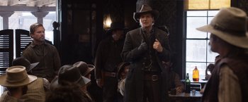 Movie still from “A Million Ways to Die in the West” (2014), directed by Seth MacFarlane – A group of people in a room with hats on; Medium shot, Over the shoulder angle