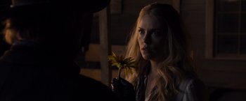 Movie still from “A Million Ways to Die in the West” (2014), directed by Seth MacFarlane – A woman holding a yellow flower while wearing gloves; Close Up shot, Over the shoulder angle