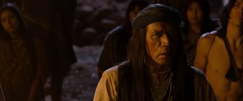 Movie still from “A Million Ways to Die in the West” (2014), directed by Seth MacFarlane – An old man with long black hair wearing a black hat; Close Up shot, Over the shoulder angle