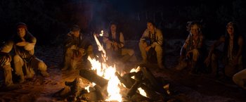 Movie still from “A Million Ways to Die in the West” (2014), directed by Seth MacFarlane – A group of people sitting around a fire at night; Wide shot, High angle