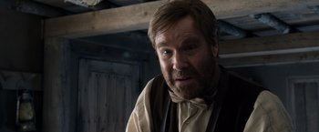 Movie still from “A Million Ways to Die in the West” (2014), directed by Seth MacFarlane – A man with a beard wearing a brown vest and tie; Close Up shot, Over the shoulder angle