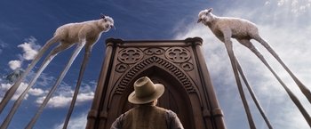 Movie still from “A Million Ways to Die in the West” (2014), directed by Seth MacFarlane – A man standing in front of a gate with two sheep; Wide shot, Low angle