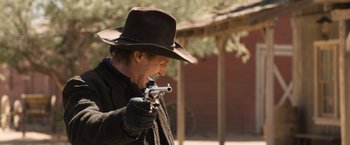 A man wearing a hat and holding a gun in his hand