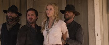 Movie still from “A Million Ways to Die in the West” (2014), directed by Seth MacFarlane – Two men and a woman standing next to each other in front of a building; Medium shot, Low angle