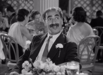 Movie still from “A Night at the Opera” (1935), directed by Sam Wood – A black and white photo of a man sitting at a table; Close Up shot, Over the shoulder angle