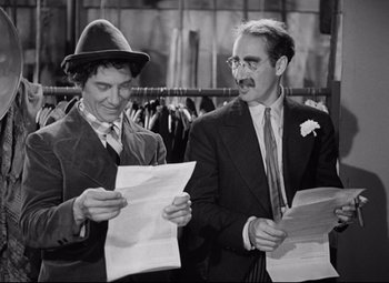 Movie still from “A Night at the Opera” (1935), directed by Sam Wood – A couple of men standing next to each other holding papers; Medium shot, Over the shoulder angle