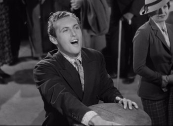 Movie still from “A Night at the Opera” (1935), directed by Sam Wood – A man in a suit and tie sitting down laughing; Medium shot, High angle