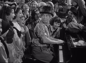 Movie still from “A Night at the Opera” (1935), directed by Sam Wood – An old photo of a man playing the piano in front of a crowd; Medium shot, High angle