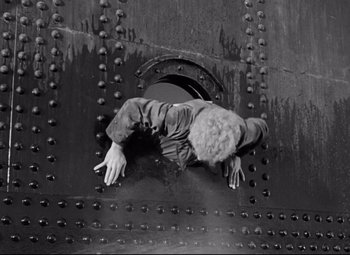 Movie still from “A Night at the Opera” (1935), directed by Sam Wood – A man hanging upside down on a metal wall; Medium shot, Overhead angle