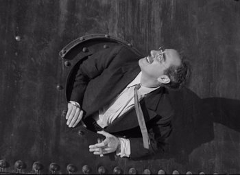 Movie still from “A Night at the Opera” (1935), directed by Sam Wood – A black and white photo of a man in a suit and tie; Medium shot, Overhead angle