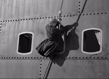 Movie still from “A Night at the Opera” (1935), directed by Sam Wood – A man is climbing up the side of an airplane; Wide shot, Overhead angle