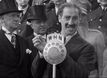Movie still from “A Night at the Opera” (1935), directed by Sam Wood – An old photo of a man holding a parking meter; Close Up shot, Low angle