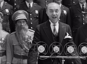 Movie still from “A Night at the Opera” (1935), directed by Sam Wood – An old photo of a man speaking at a ceremony; Medium shot, Low angle