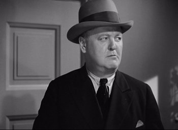 Movie still from “A Night at the Opera” (1935), directed by Sam Wood – A man wearing a suit and a hat; Close Up shot, Low angle