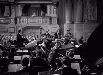 Movie still from “A Night at the Opera” (1935), directed by Sam Wood – A group of people sitting in a room with instruments; Extreme Wide shot, High angle