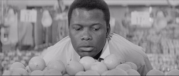 A black and white photo of a man surrounded by apples
