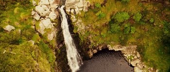 Movie still from “A Perfect Getaway” (2009), directed by David Twohy – An aerial view of a waterfall in the middle of a lush green forest; Extreme Wide shot, Overhead angle