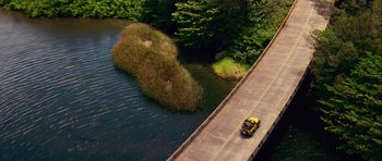 Movie still from “A Perfect Getaway” (2009), directed by David Twohy – A car driving down a road next to a body of water; Extreme Wide shot, Overhead angle